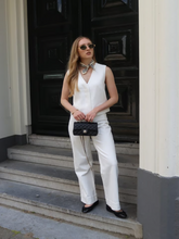 A woman wears white vest and jeans